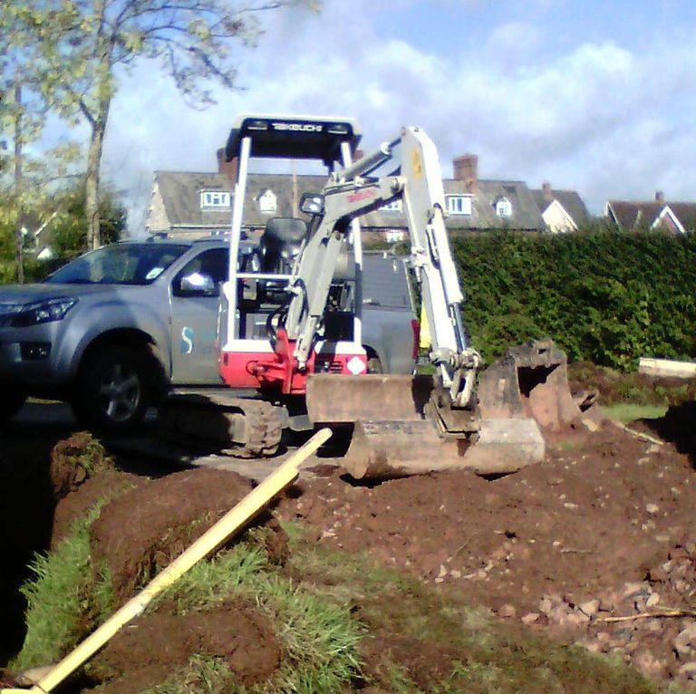 A digger digging up dirt for drainage repairs